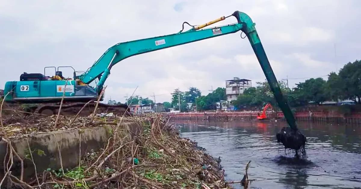 An excavator removing silt and waste from a river