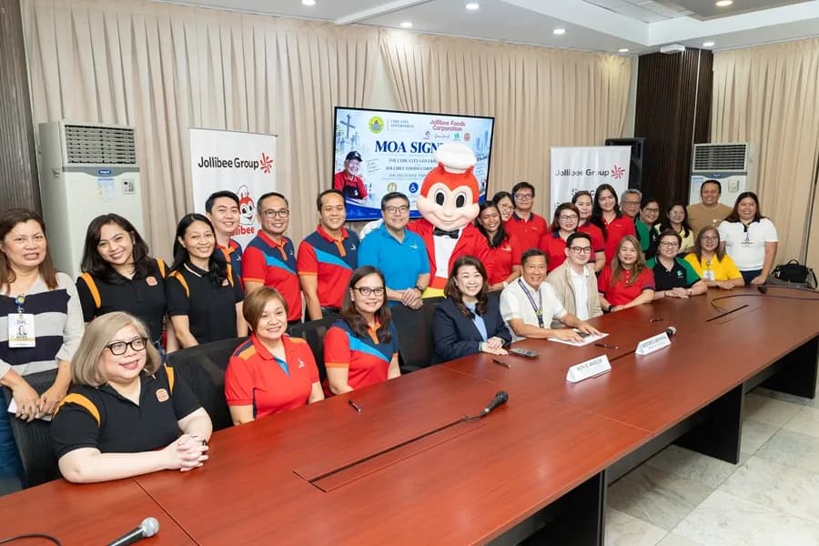 Jollibee Group and Cebu City officials pose with the Jollibee mascot at a signing table