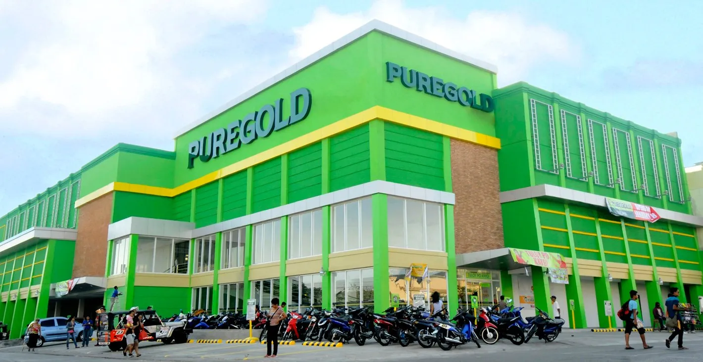 A green-and-yellow Puregold supermarket building with motorcycles parked in front