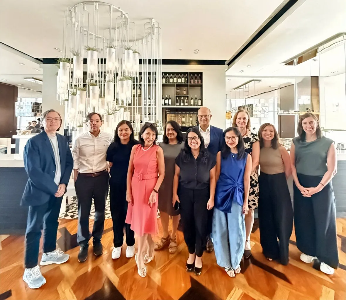 A group of women and men smiling together in a restaurant lobby