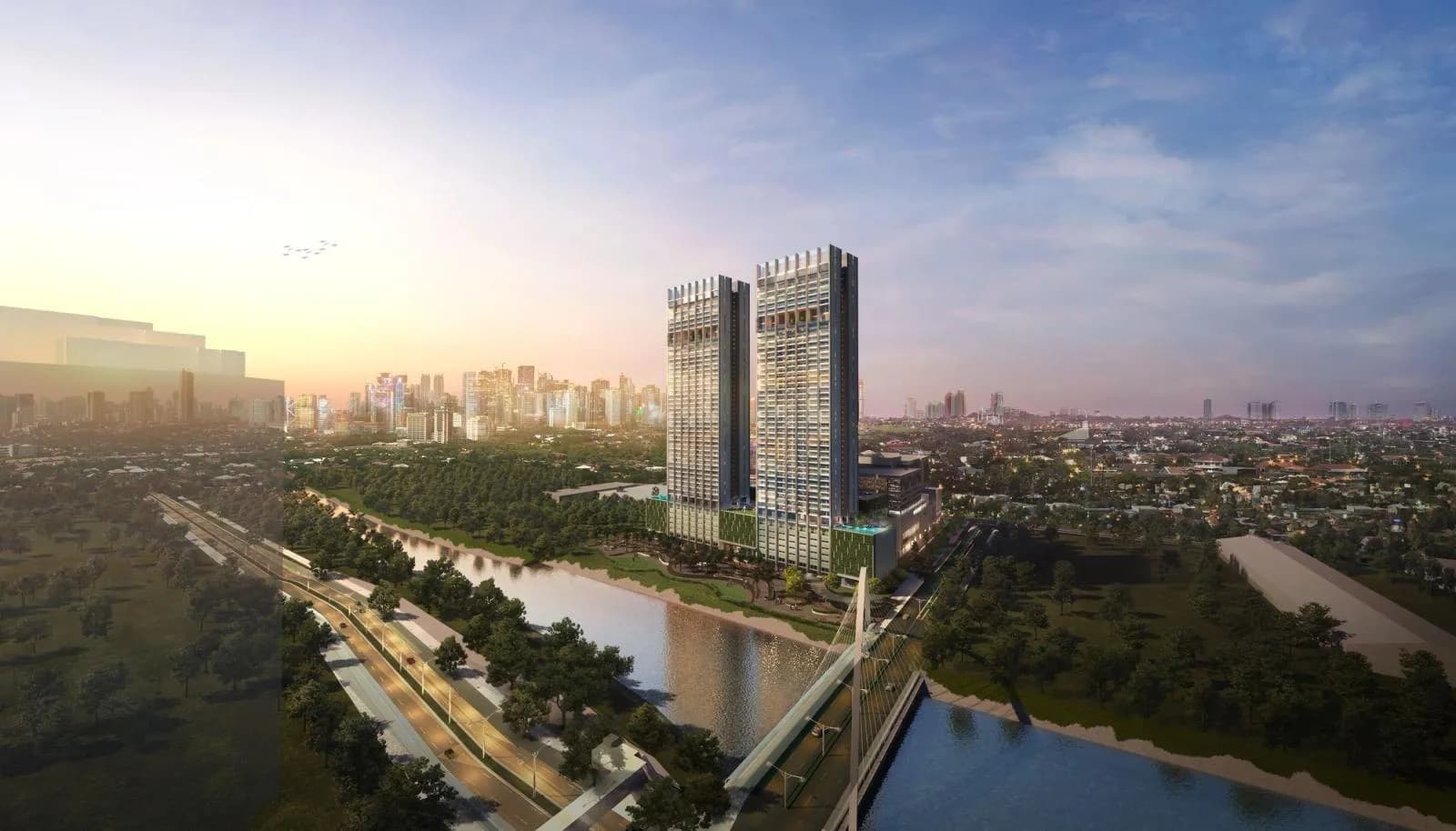 Twin residential towers beside a river and green parkland at sunset